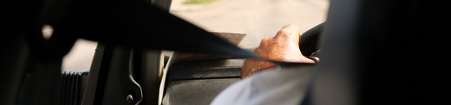 mature male driver with his seatbelt on and his hand on the steering wheel